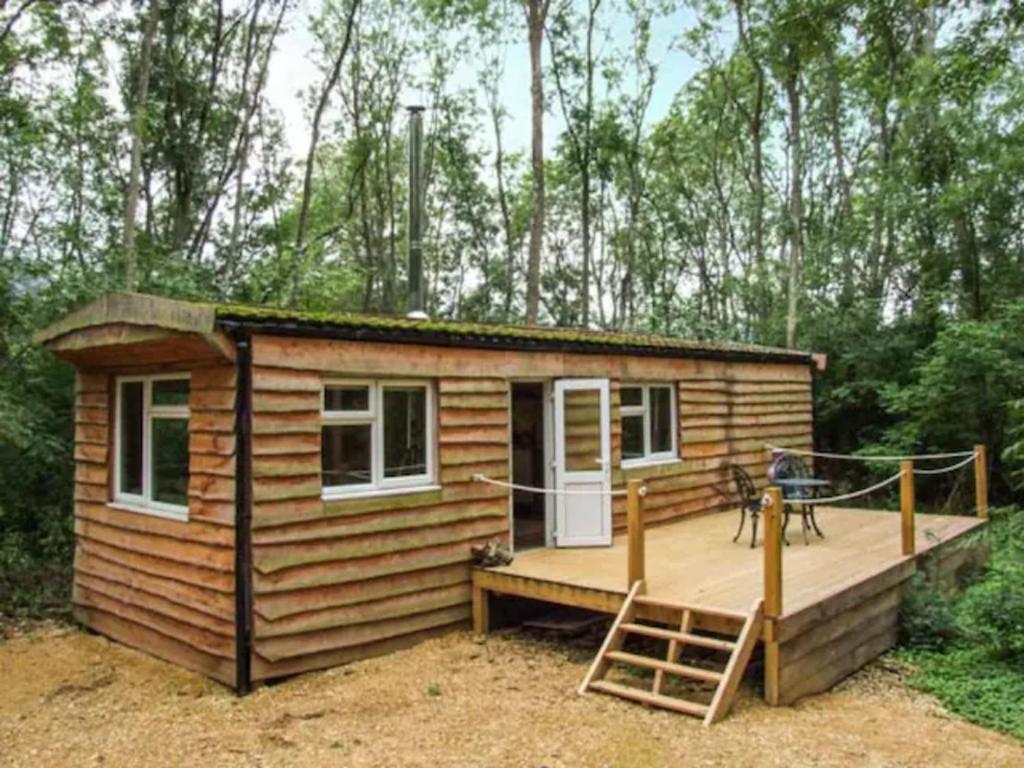 uma cabana de madeira com um alpendre e um deque em Riverwood Lodges em Lechlade