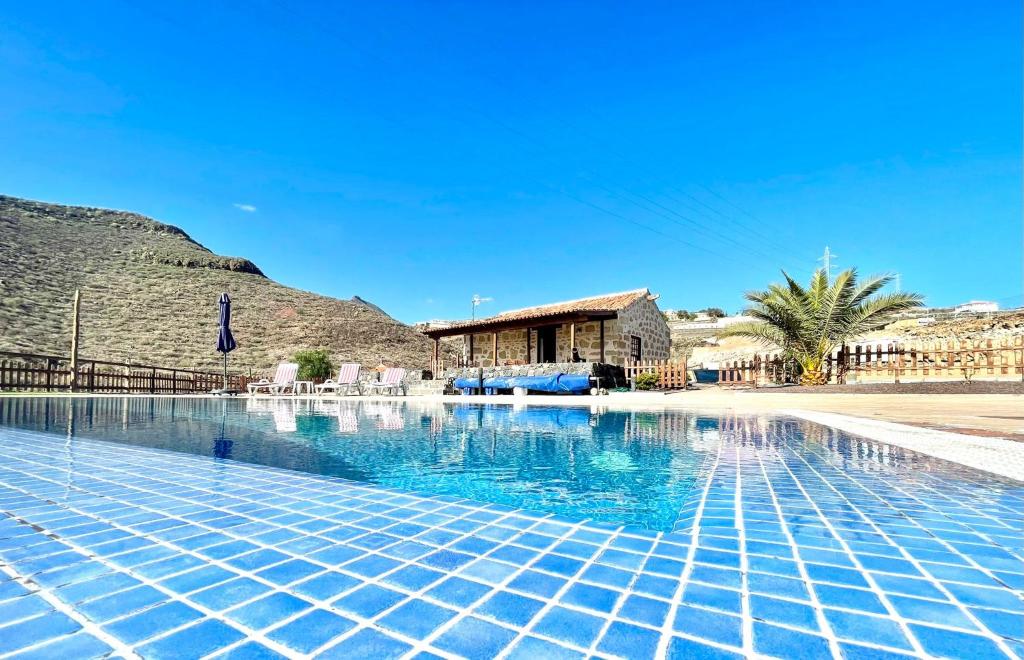 a swimming pool with blue tiles on the ground at Rural house with private pool, BBQ, and views of the Atlantic Ocean in Tenerife South in San Miguel de Abona