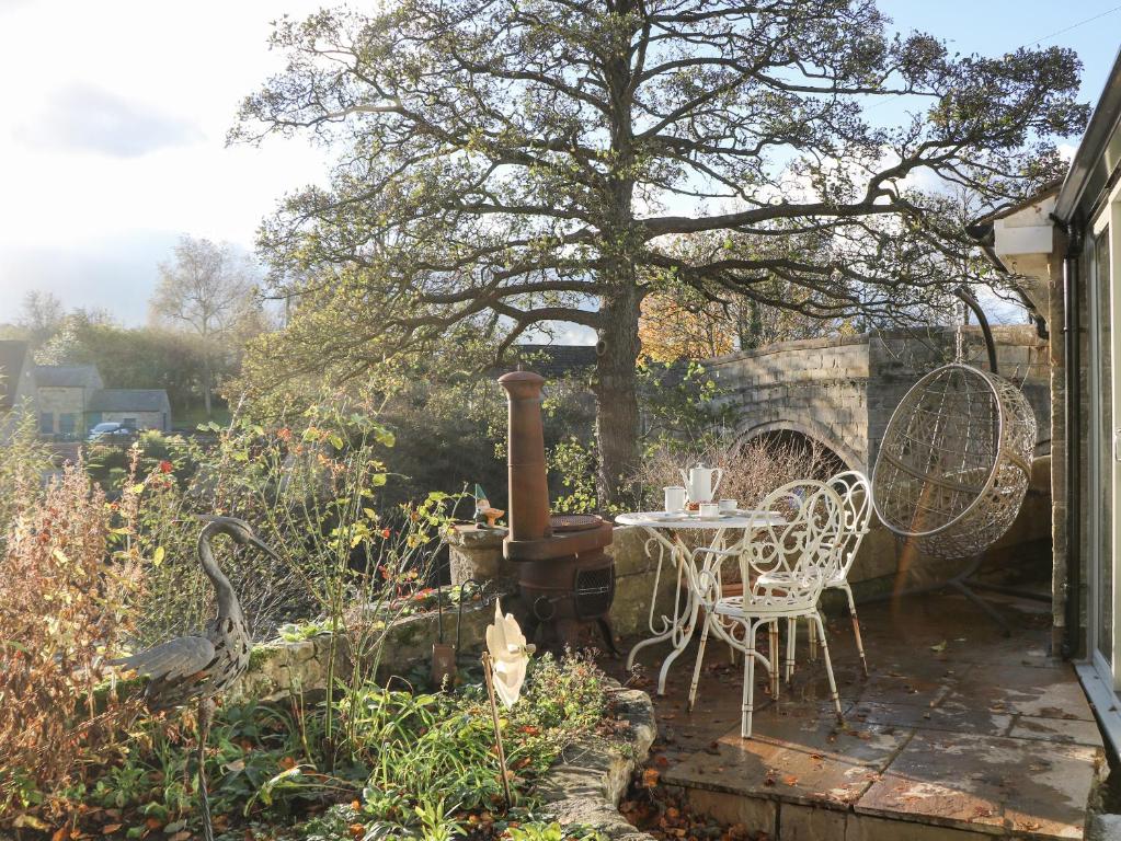 un patio con mesa y sillas en un jardín en Toll Bar Cottage, en Bakewell