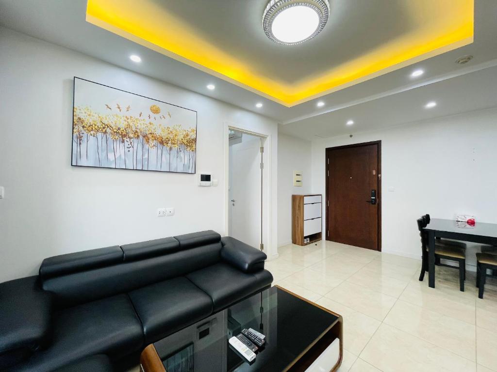 uma sala de estar com um sofá de couro preto e um piano em VNRooms - 2BR Vinhomes D'Capitale/ LAKE VIEW/ 23Fl em Hanói