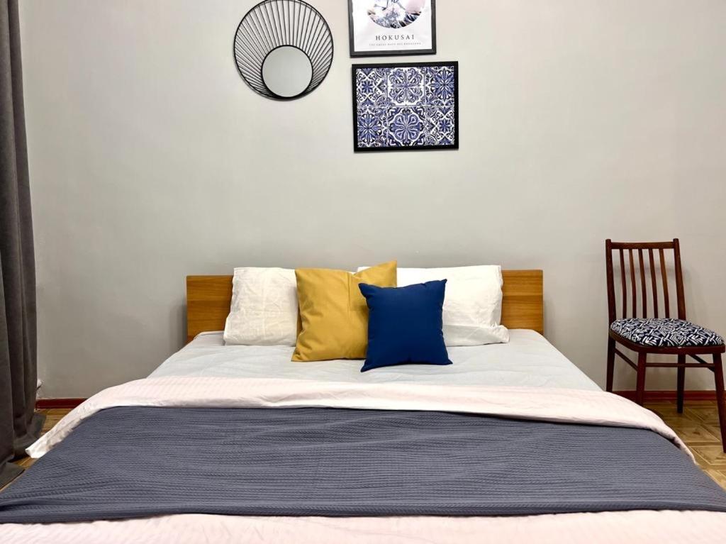 a bedroom with a bed with blue and yellow pillows at Квартира на Атакенте у Выставки in Almaty