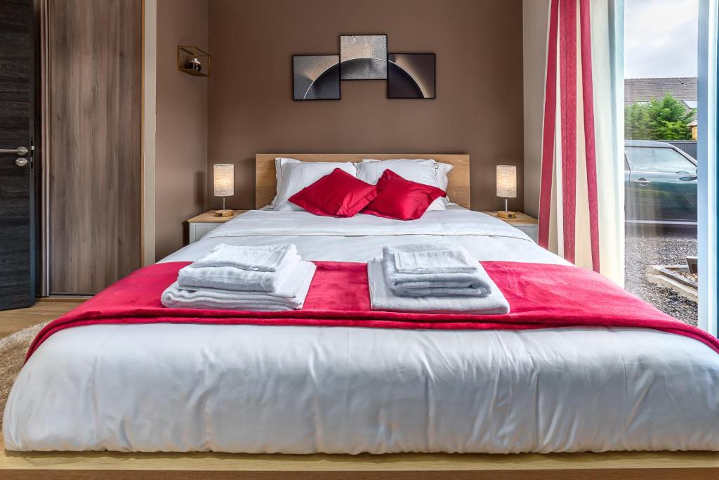 a bedroom with a large bed with red pillows at SUITE ET CHAMBRES COSY CHEZ A&M -ELEGANT HOME, CALME, CAMPAGNE, PARKING gratuit in Épône