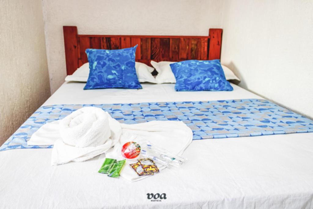 2 camas con sábanas blancas y almohadas azules en Pousada Aconchego Recanto Canto Do Mar, en Bairro da Enseada