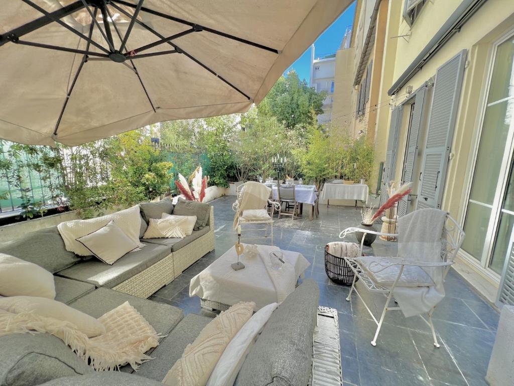 une terrasse avec un canapé, des chaises et un parasol dans l'établissement Superbe Appartement de 105 m2, hyper centre avec Terrasse, parking, à 5 min de la mer, à Nice