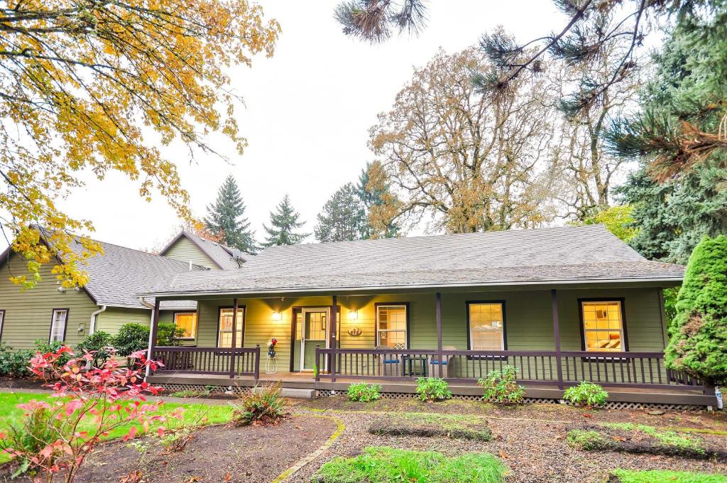 a green house with a porch and trees at Milwaukie Home with Covered Porch Dogs Welcome! in Milwaukie