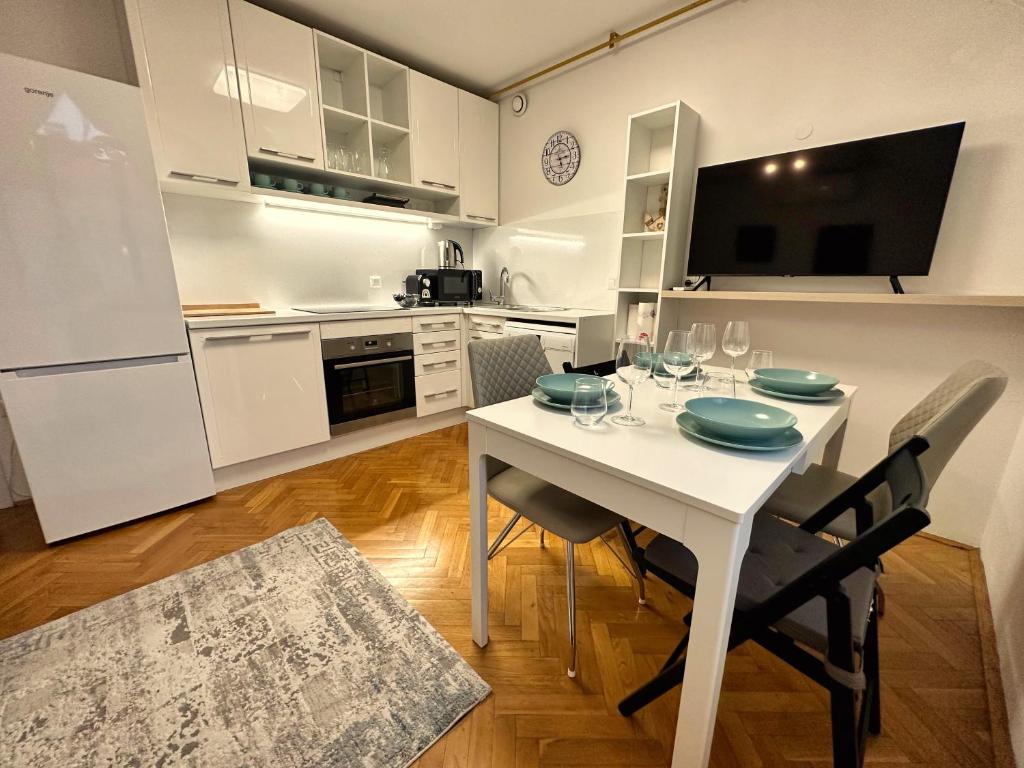 a white kitchen with a white table and chairs at Charming City Loft Apartment in Ljubljana