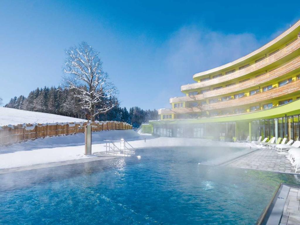 a swimming pool in front of a building in the snow at DAS SIEBEN - Adults Only in Bad Häring