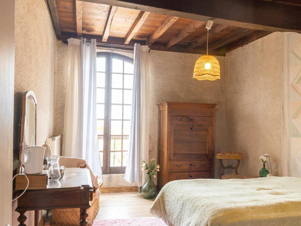 Schlafzimmer mit einem Bett, einem Tisch und einem Fenster in der Unterkunft Gîte d'étape la P'tite Graine in Auvillar