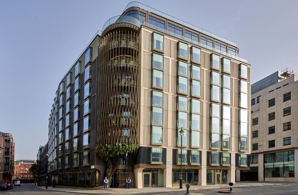um grande edifício de vidro com uma árvore em frente em The BoTree - Preferred Hotels and Resorts em Londres