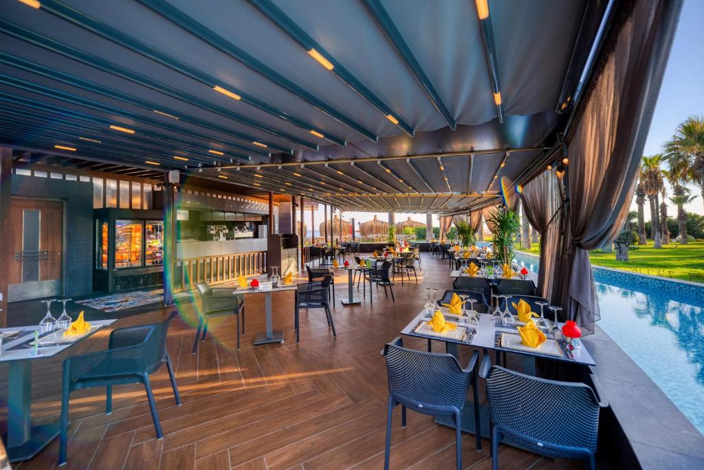 a restaurant with tables and chairs and a swimming pool at Megasaray Club Belek in Belek