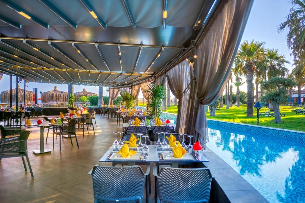 a restaurant with a pool with tables and chairs at Megasaray Club Belek in Belek