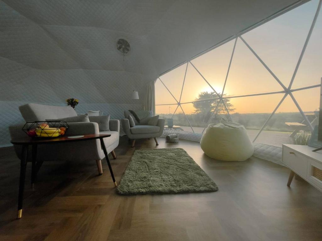 a living room with a table and a large window at Sunset Ridge - Luxury Geodesic Dome set in the beautiful countryside in Porkellis
