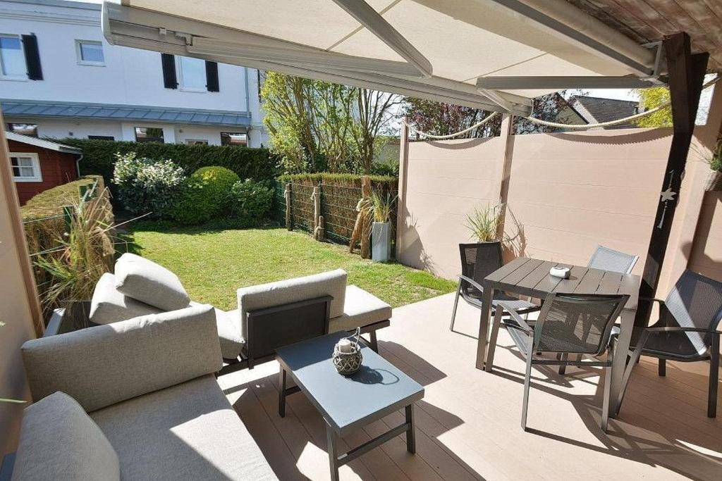 eine Terrasse mit einem Sonnenschirm, einem Tisch und Stühlen in der Unterkunft Haus Möwenstr 9, Haus 6 in Grömitz