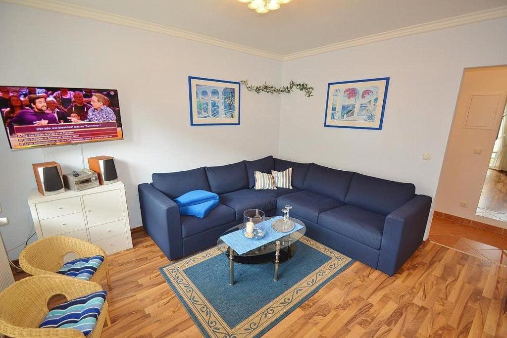 uma sala de estar com um sofá azul e uma mesa em Möwe Whg 1 em Grömitz