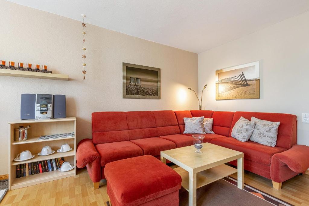 uma sala de estar com um sofá vermelho e uma mesa em Nautilus Whg 19 em Grömitz