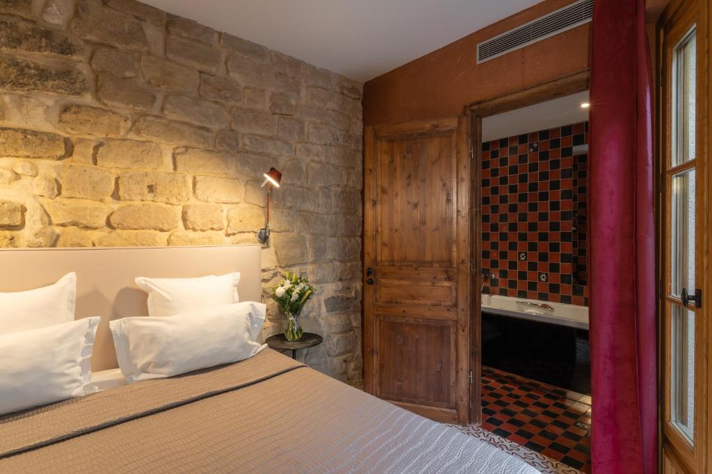 sypialnia z łóżkiem i kamienną ścianą w obiekcie Hôtel Prince de Conti w Paryżu