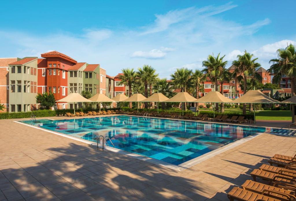 a pool at a resort with chairs and umbrellas at Megasaray Club Belek in Belek