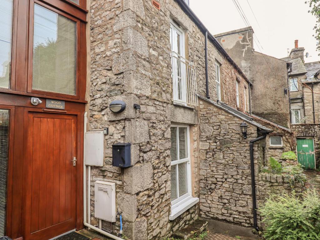 an old stone building with a wooden door at Wood Cottage in Kendal
