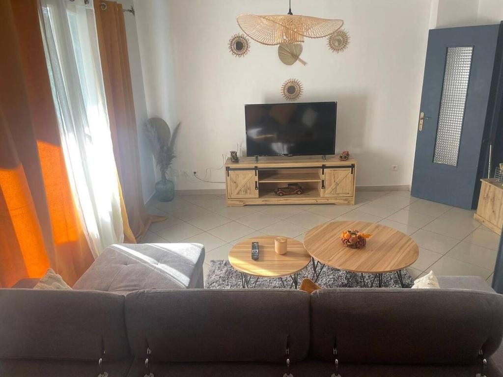 Il comprend un salon doté d'un canapé et d'une télévision à écran plat. dans l'établissement Appartement proche gare TGV, à Nîmes