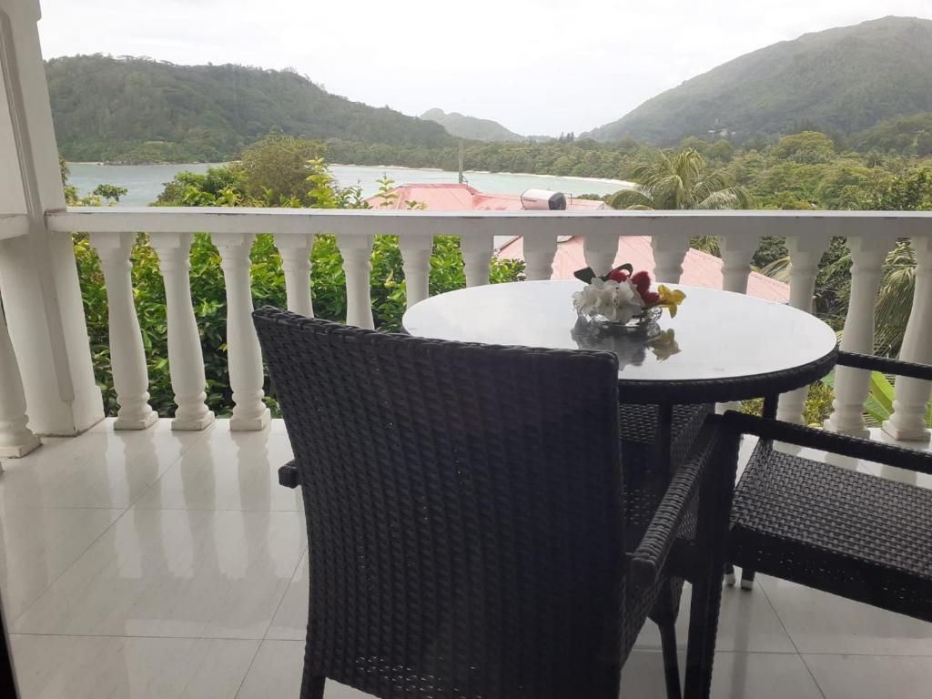 a table and chairs on a balcony with a view at Gigi's Self Catering Apartment in Port Glaud