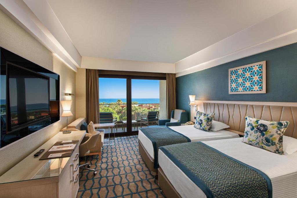 a hotel room with two beds and a flat screen tv at Megasaray Club Belek in Belek
