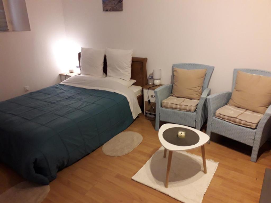 a bedroom with a bed and two chairs and a table at Appart-Hôtel Résidence Maloc in Malaucène