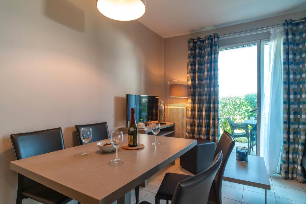 - une salle à manger avec une table, des chaises et des verres à vin dans l'établissement Les Thermes 408 - Appt pour 4 avec piscine partagée, à Concarneau