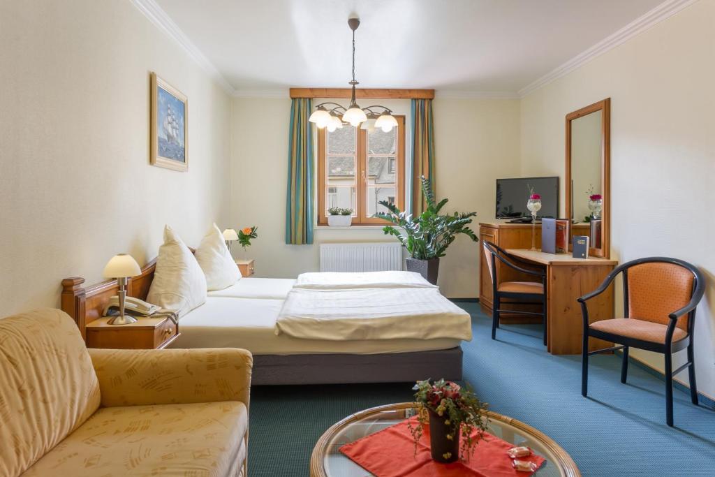 a hotel room with a bed and a table at Logis Hotel-Restaurant Petry in Vianden