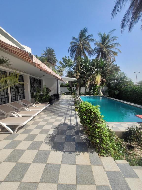 a resort with a swimming pool and palm trees at Villaannadakar in Dakar