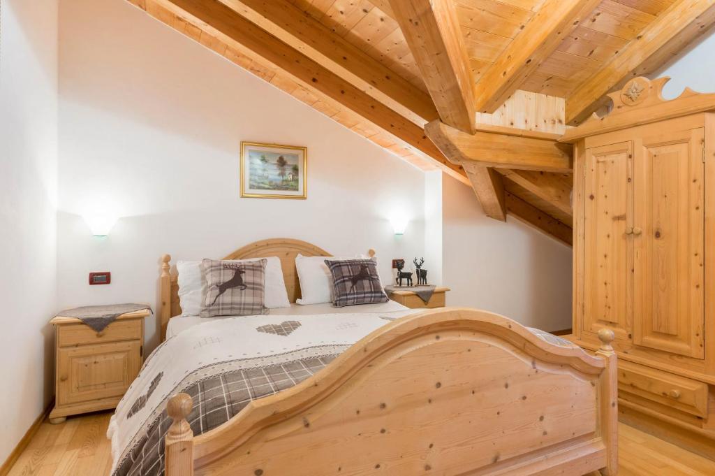 a bedroom with a wooden bed and wooden ceilings at Villetta Clara in Vigo di Fassa