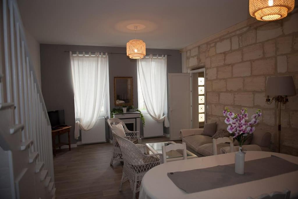 ein Wohnzimmer mit einem Sofa und einem Tisch in der Unterkunft Bel appartement en pierre de 100 m2 avec cour. in Margaux