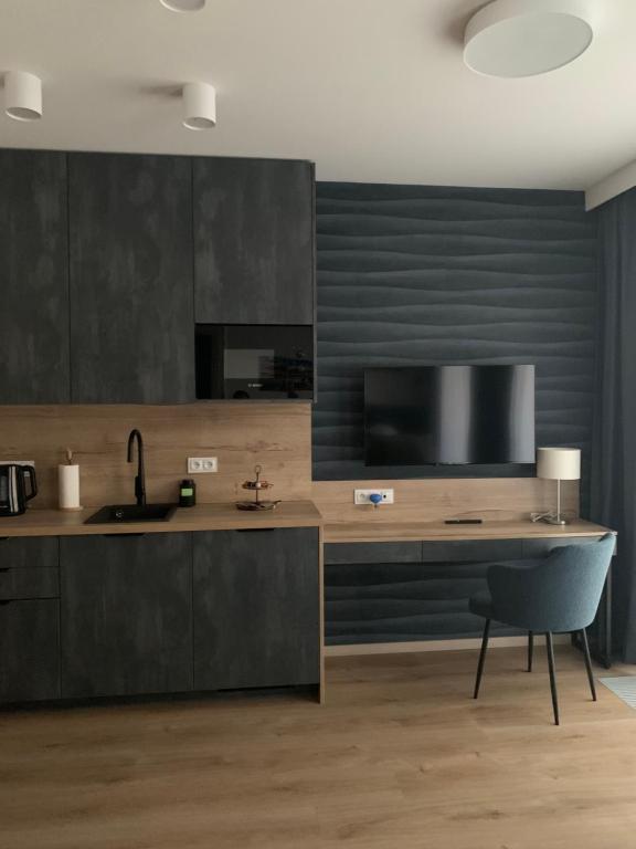 a kitchen with a sink and a desk with a television at REMAR - Apartamentai prie Biale Ežero in Augustów