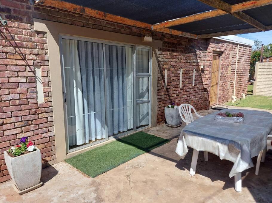 a patio with a table and chairs and a window at Shades of grey in Oudtshoorn