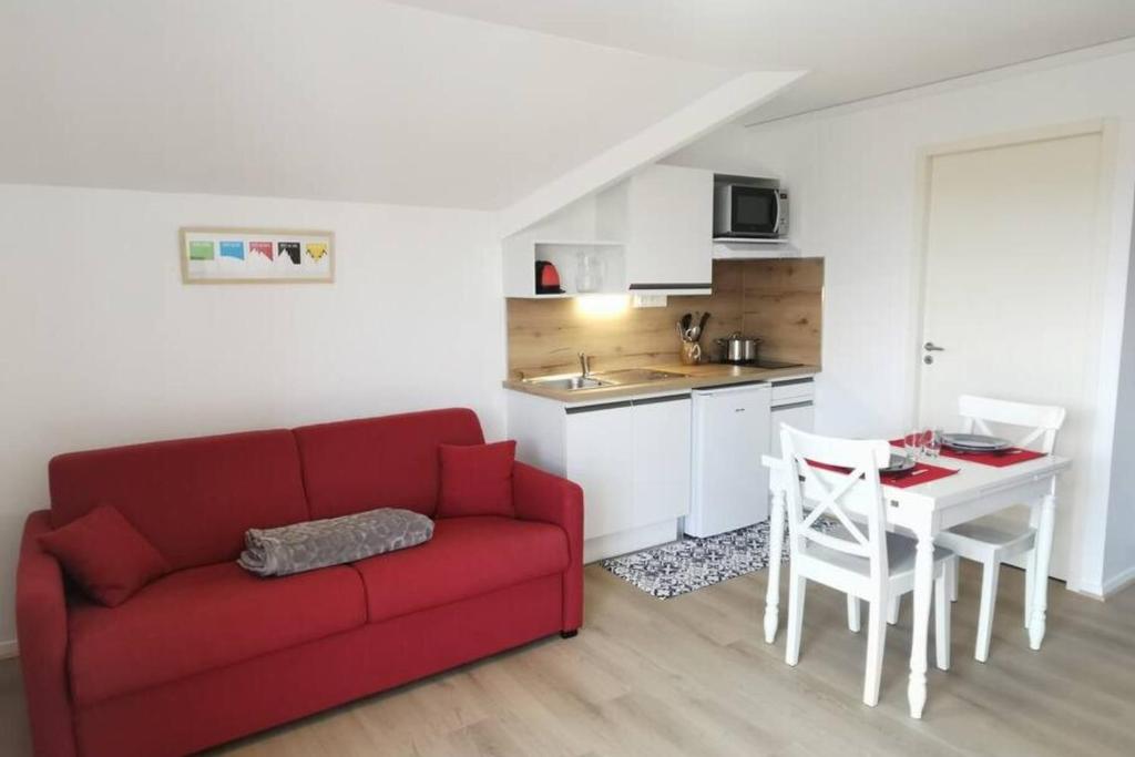 a living room with a red couch and a kitchen at Studio 2 pers avec accès piscine et sauna in Les Déserts