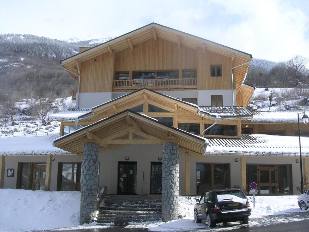 a large wooden house with a car parked in the snow at Hameau 8 102 - SPA & PISCINE appartement 4 pers in Orelle