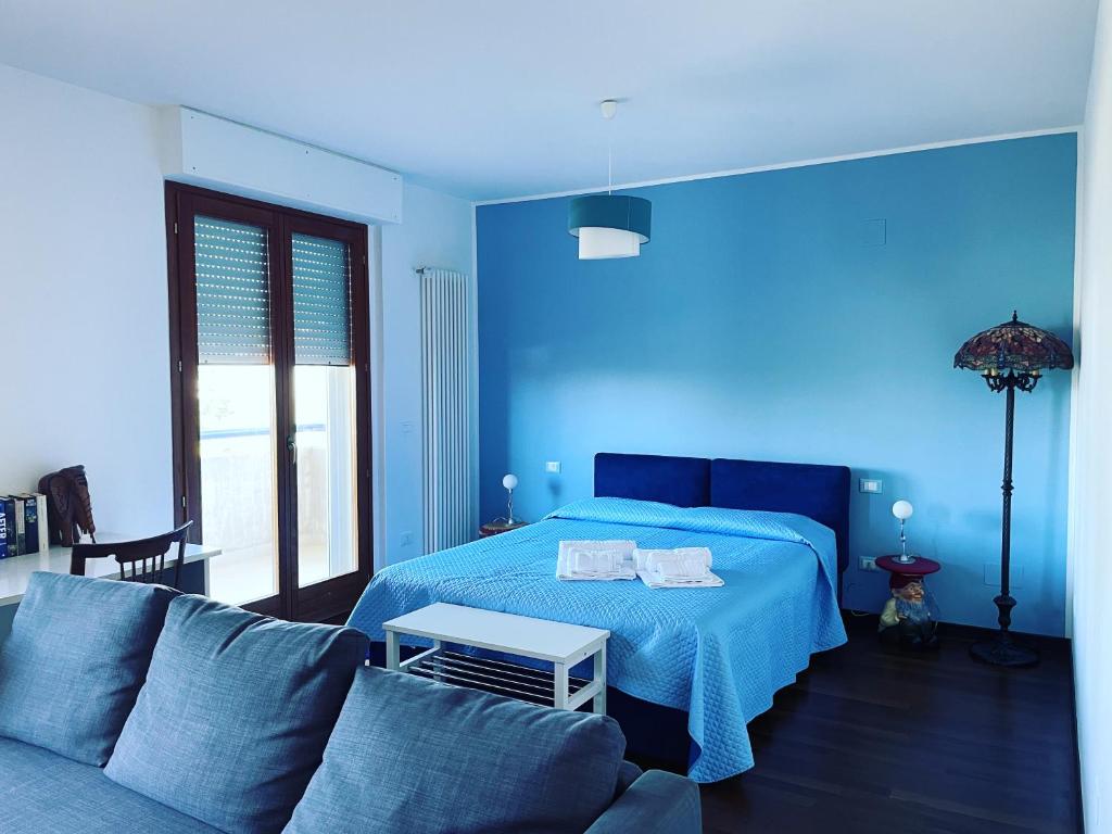 ein blaues Schlafzimmer mit einem Bett und einem Sofa in der Unterkunft Attico Vista e Fronte mare ZaffiroBlu con posto auto in Montesilvano