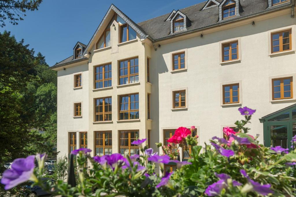 a building with purple flowers in front of it at Logis Hotel-Restaurant Petry in Vianden