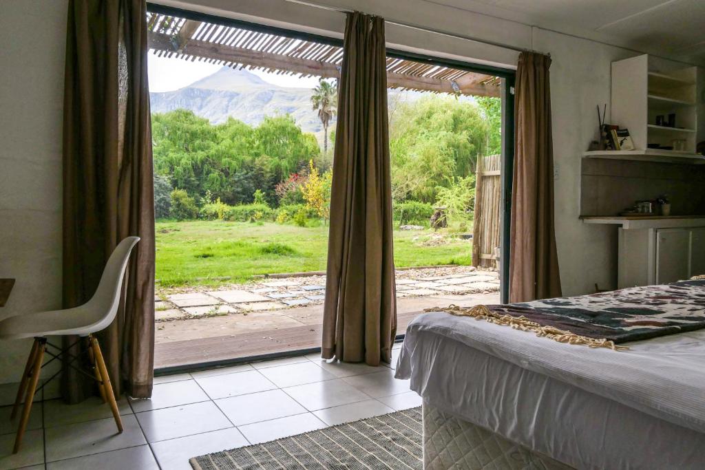 a bedroom with a bed and a large sliding glass door at Canary Cottage in Greyton