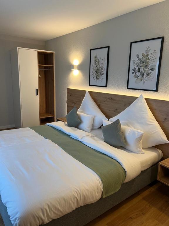ein Schlafzimmer mit einem großen Bett mit weißer Bettwäsche und Kissen in der Unterkunft Vorgebirgsblick - Restaurant Biergarten Gästehaus in Bornheim