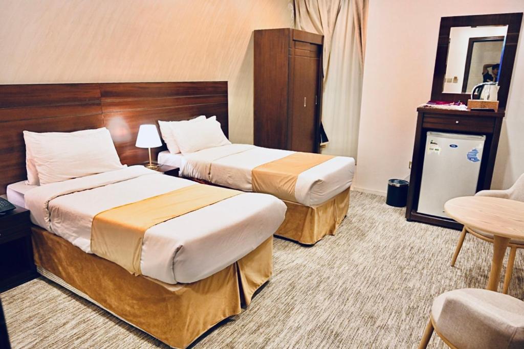 a hotel room with two beds and a table at فندق جولدن العزيزية in Makkah