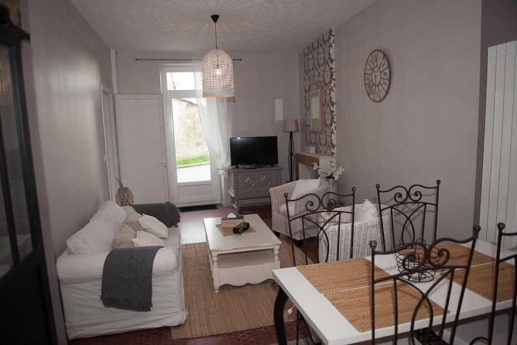 ein Wohnzimmer mit einem Sofa und einem Tisch in der Unterkunft bel appartement en pierre de 88 M2 charme d’antan in Margaux