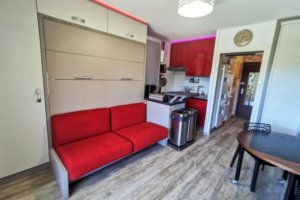 a living room with a red couch in a kitchen at Cozy apartment "WAPITI" at the foot of the slopes in Les Déserts