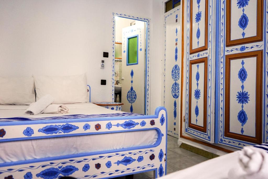 Dormitorio azul y blanco con cama y espejo en Hotel Marrakech, en Chefchaouen