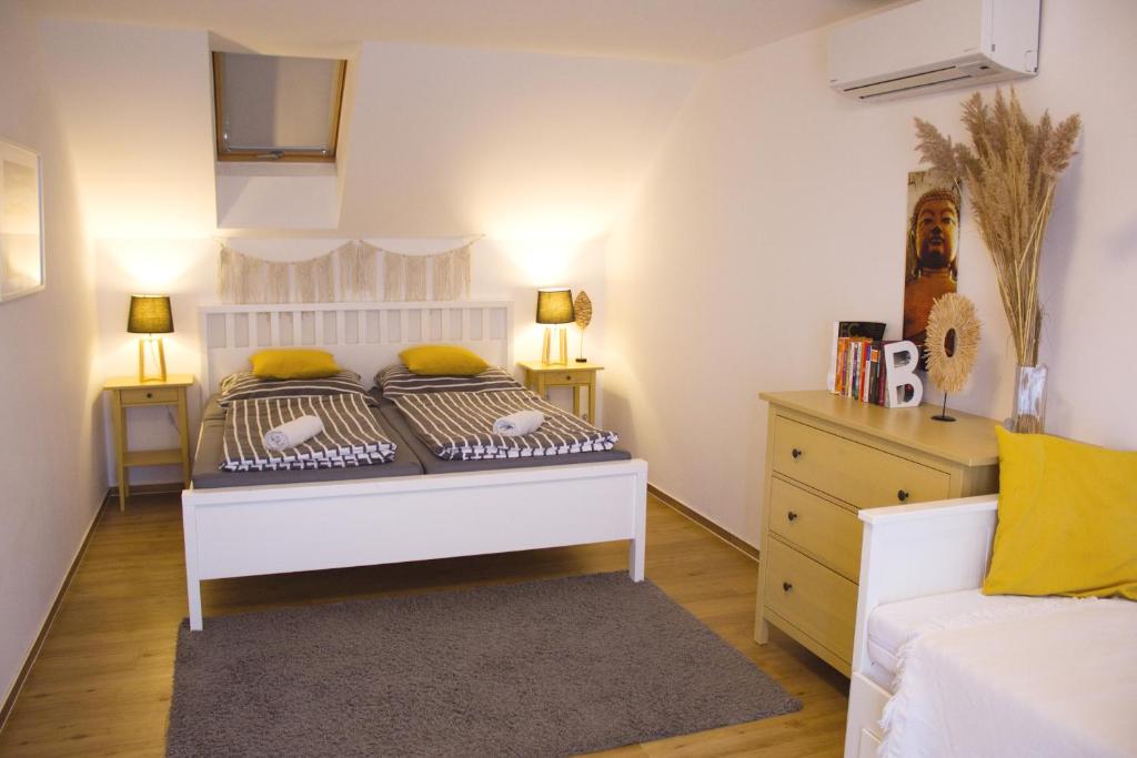 a bedroom with a white bed with yellow pillows at Duplex apartmán Pálava in Dolní Dunajovice