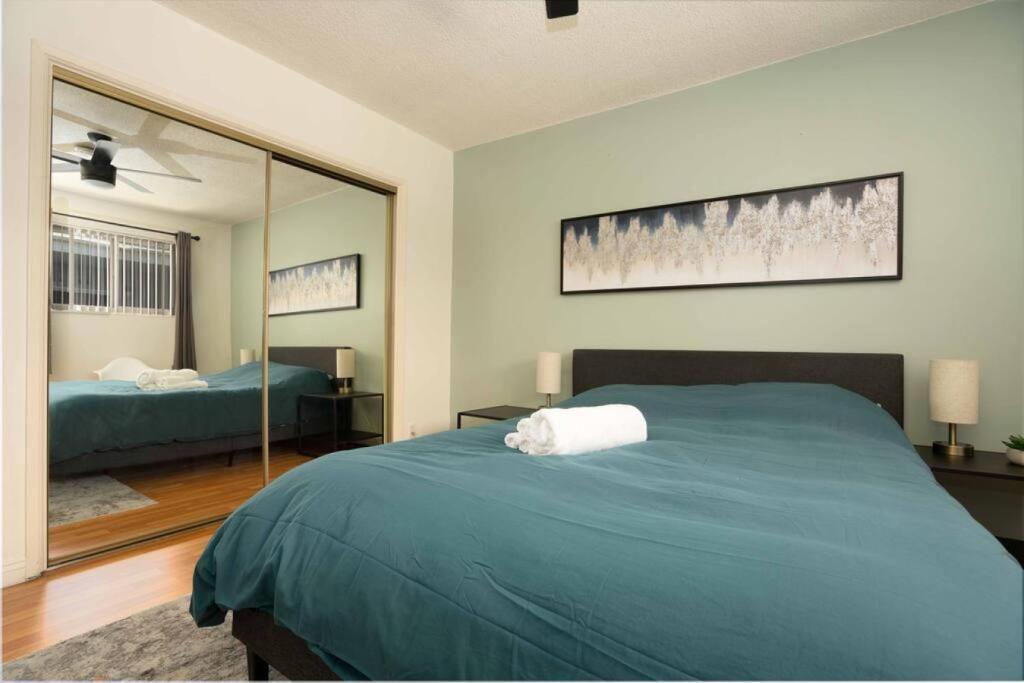 Un dormitorio con una gran cama verde y un espejo en Amazing 3BR Home near Hollywood DTLA, en Los Ángeles