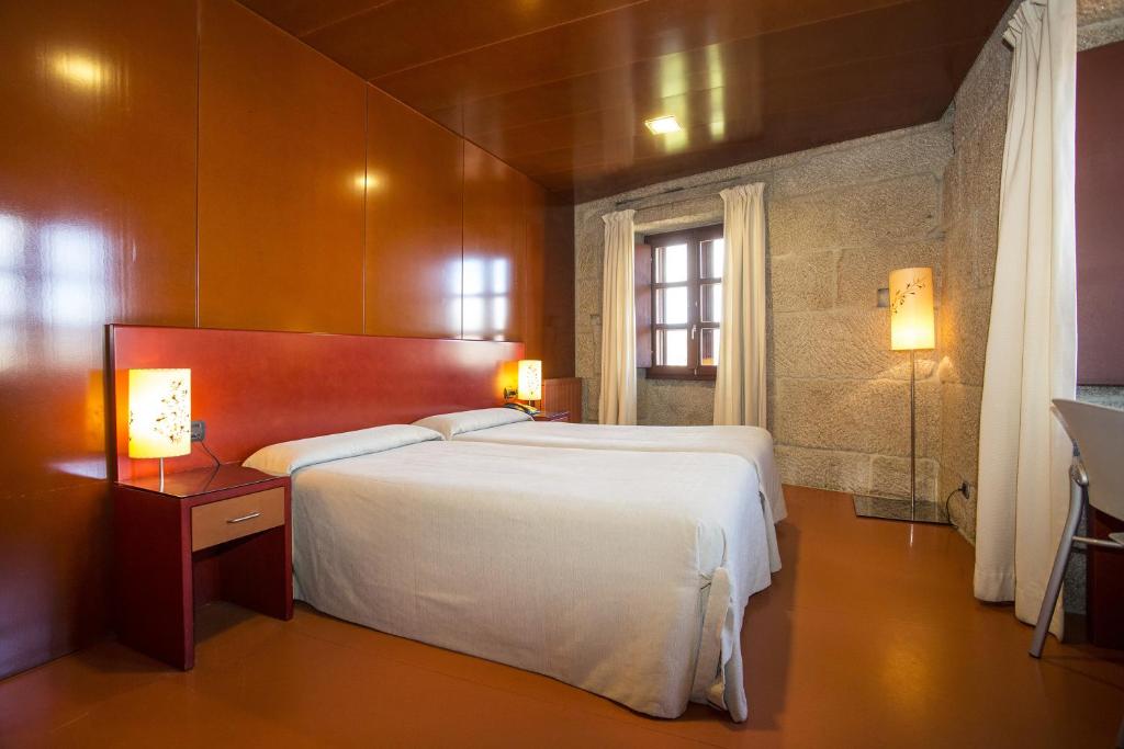 - une chambre avec un grand lit blanc et une fenêtre dans l'établissement Casa Rural Torre Lombarda, à Allariz