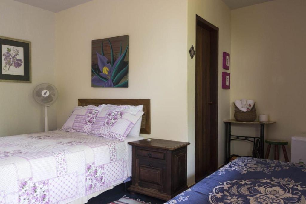 a bedroom with a bed and a nightstand with a bed sidx sidx at Pousada Luz do Sol in Sao Jorge