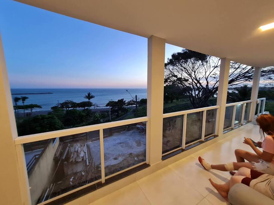 two women sitting on a balcony looking out at the ocean at Frente Mar Vista Incrível Meaípe in Guarapari