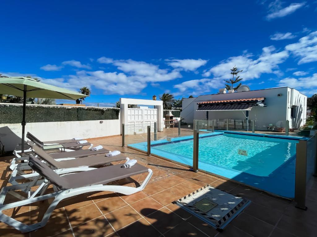 a swimming pool with chaise lounge chairs and an umbrella at Villa Emilia by Best Holidays Fuerteventura in Corralejo
