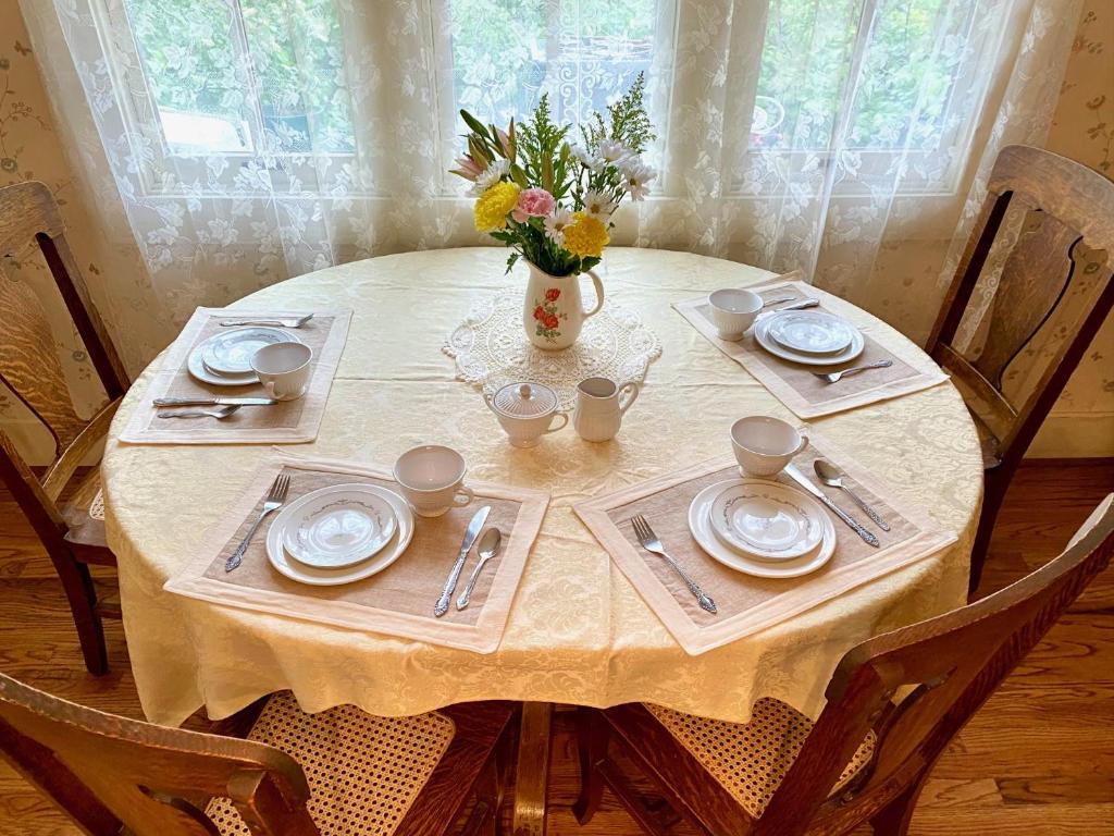 una mesa con platos y un jarrón de flores. en Pansy’s Parlor Bed & Breakfast, en Golden